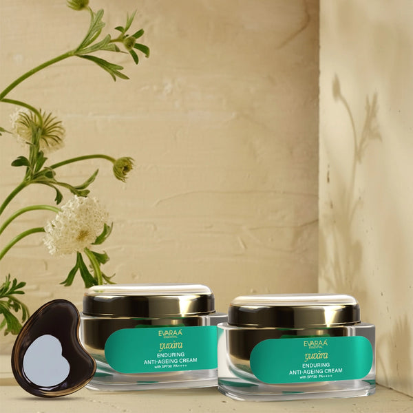 Two jars of anti-aging cream with green labels and a free Gua Sha tool on a light background with plants.
